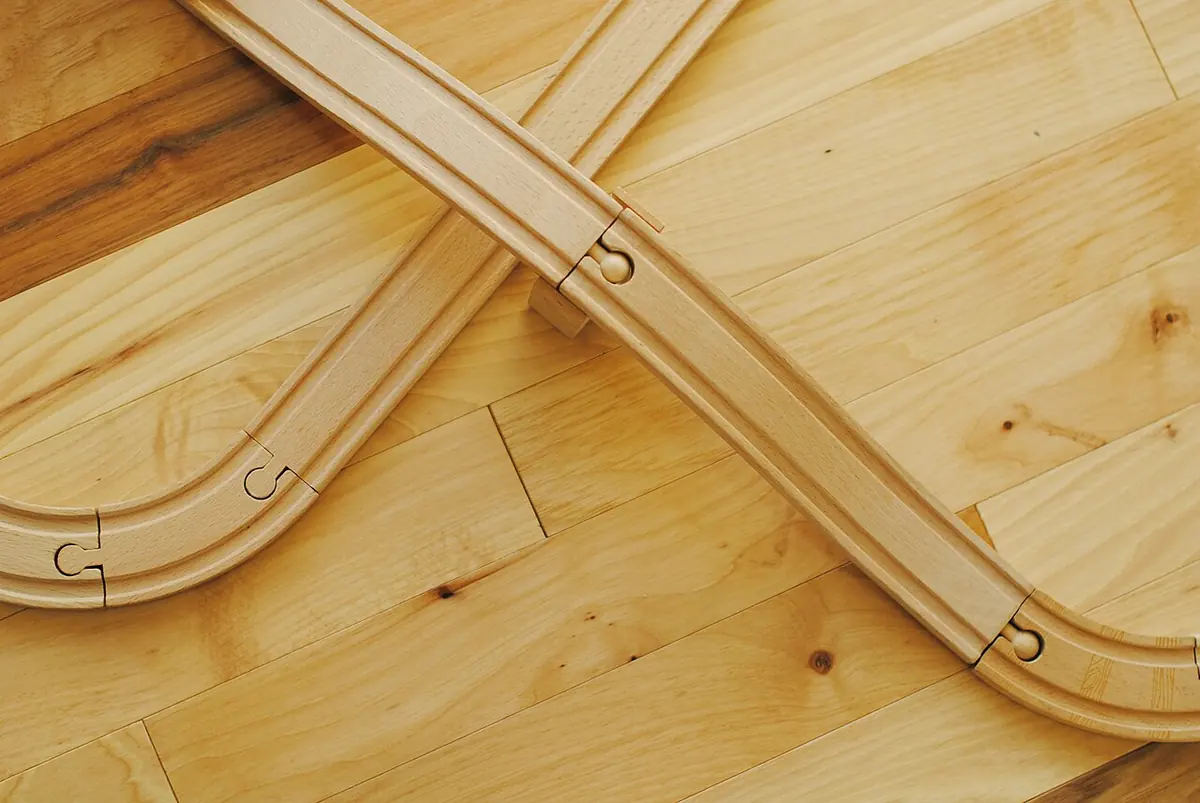 A wooden toy train track on a wooden floor