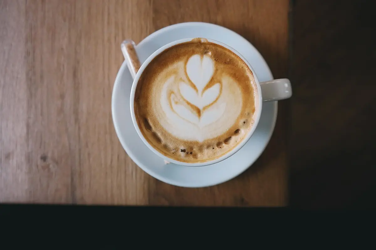 Een cappuccino met latte art op een houten tafel