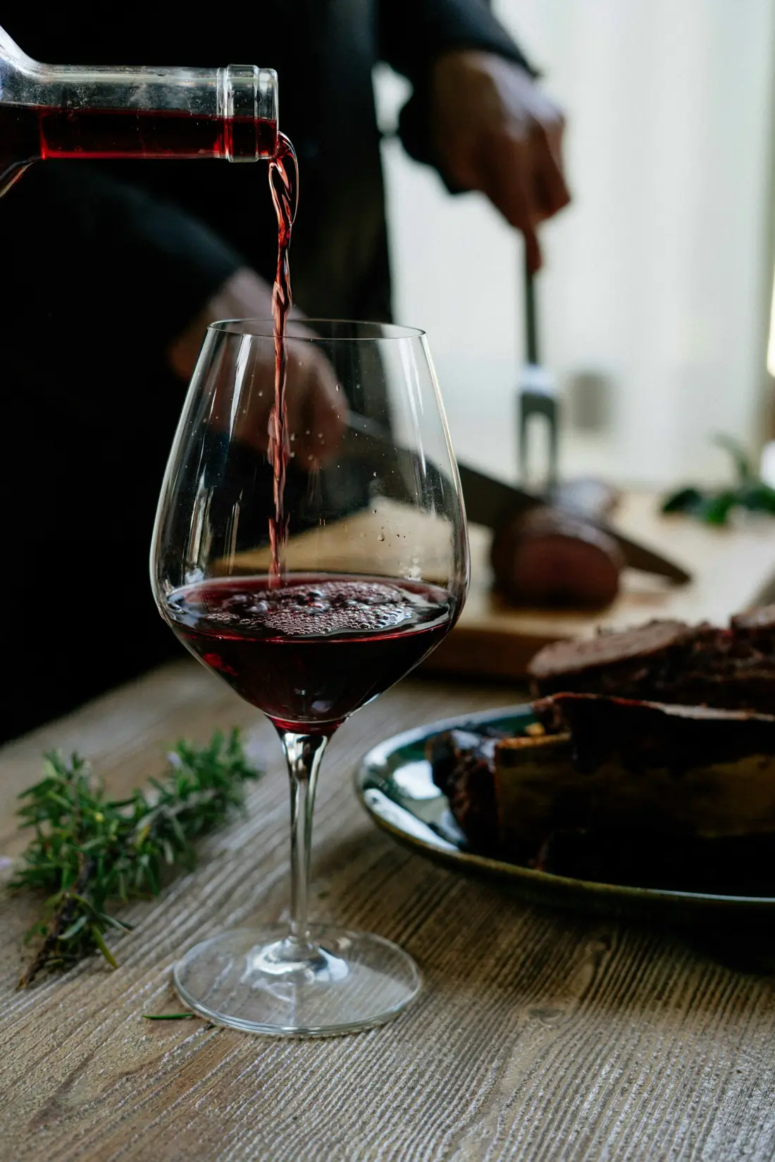 Rode wijn die aan tafel in een glas wordt geschonken